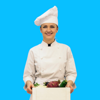 cuisinière avec une toque sur la tête et une cagette dans les mains avec des légumes dedans